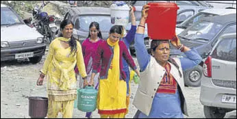  ?? DEEPAK SANSTA HT ?? Women carrying water buckets to their homes at Shanan in Shimla on Monday. The water crisis in state’s capital has increased the dependency of residents on tankers and other sources.