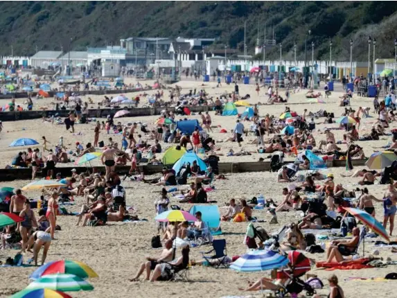  ?? (PA) ?? People enjoy the autumn sunshine on Bournemout­h beach yesterday