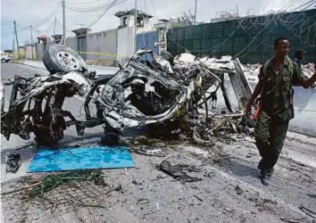  ?? AP ?? A Somali soldier stands near the wreckage of a suicide car bomb outside the UN’s office in Mogadishu on Tuesday.