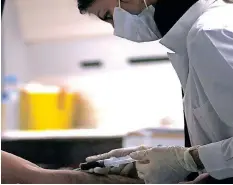  ?? ?? A NURSE draws blood for an HIV test from a Greek drug addict in a mobile HIV testing van in Omonia Square in Athens. | Reuters