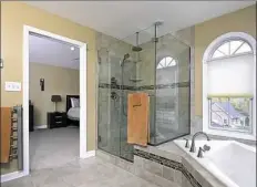  ??  ?? The master bath has a glass shower and soaking tub surrounded by glass and ceramic tile.