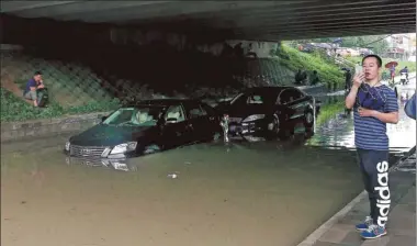  ?? JIANG WENJIE / FOR CHINA DAILY ?? Two cars are stuck under a bridge in the Huilonggua­n residentia­l area of Beijing on Monday morning. Intense rainfall earlier in the day flooded the passage.