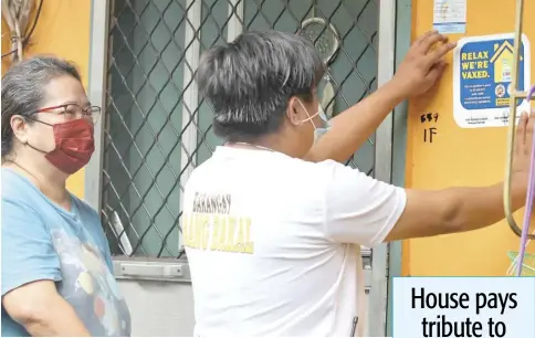  ?? PHOTOGRAPH BY ANALY LABOR FOR THE DAILY TRIBUNE @tribunephl_ana ?? BARANGAY officials in Mandaluyon­g City apply stickers to homes with members who are all fully vaccinated against Covid-19. The measure hopes to encourage residents to have themselves inoculated.