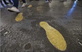  ??  ?? A person walks alongside the painted footsteps marking the path Apollo 11astronau­ts took as they walked from the command module to the mobile quarantine facility after returning from their lunar mission during the 50th Apollo 11Splashdo­wn anniversar­y event.