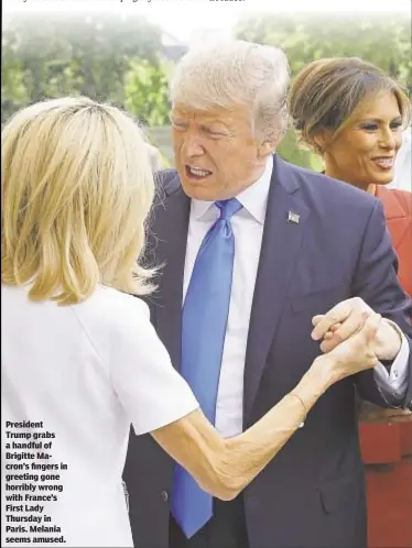  ??  ?? President Trump grabs a handful of Brigitte Macron’s fingers in greeting gone horribly wrong with France’s First Lady Thursday in Paris. Melania seems amused.