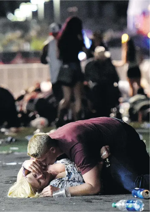  ?? DAVID BECKER / GETTY IMAGES ?? A man lies on top of a woman as others flee the Route 91 Harvest country music festival in Las Vegas late Sunday. Her condition is unknown.