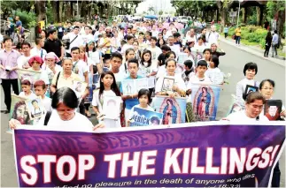  ??  ?? People hold photos of their family members, who they say were killed due to their alleged involvemen­t in illegal drugs, during a protest against extra-judicial killings while marching in an open area of a Roman Catholic Church in Paranaque city, metro...