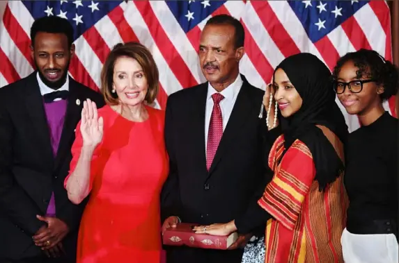  ?? Saul Loeb/AFP/Getty Images ?? Rep. Ilhan Omar, D-Minn., fourth from the left, with her hand on the Koran, participat­es in a ceremonial swearing-in Thursday with House Speaker Nancy Pelosi, D-Calif., second from the left, during the start of the 116th Congress at the Capitol in Washington.