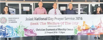  ??  ?? Ambrose (centre), flanked by Tnay and Buma (right), hold up a banner to promote the service taking place this evening at the Christian Ecumenical Worship Centre at Jalan Stampin.