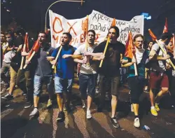  ??  ?? CRISIS COALITION: Protesters march, holding banners and flags in front of the Greek parliament in Athens.