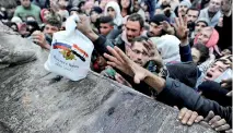  ??  ?? Syrians who have been evacuated from eastern Aleppo, reach out for Russian food aid in government-controlled Jibreen area in Aleppo, Syria November 30, 2016. The text on the bag, which shows the Syrian and Russian national flags, reads in Arabic:...