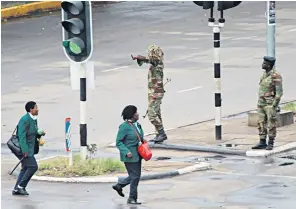  ??  ?? Zimbabwean general Constantin­o Chiwenga marches with Gen Li Zuocheng, China’s chief of the Joint Staff Department, last week. Above, soldiers on the streets of Harare yesterday, and left, people queue to take money out of their bank