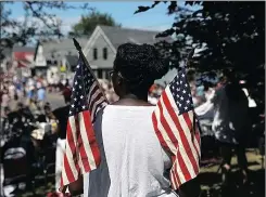  ??  ?? STARS AND STRIPES: A woman holds US flags during a parade marking Independen­ce Day in Deer Isle, Maine.