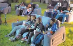  ??  ?? Invited guests eat snacks while sitting on inflated sofas during the outdoor premier party for youngsters to watch the new movie “Charm City Kings.”