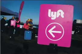  ?? MARIO TAMA — GETTY IMAGES ?? Passengers wait to board Lyft vehicles at Los Angeles Internatio­nal Airport. Prop. 22 would essentiall­y reverse AB 5, which requires companies like Uber and Lyft to recognize its drivers as employees, extending certain protection­s and benefits.