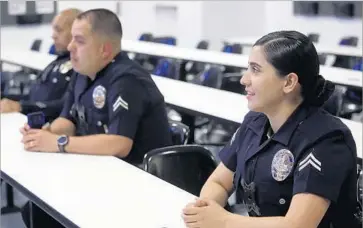  ?? Photograph­s by Genaro Molina Los Angeles Times ?? LAPD OFFICER Nancy Rodriguez, 29, right, attends roll call. She was 4 when the riots broke out, and her most vivid memory of that time is of a party dress that was lost when a nearby dry cleaner was burned down.