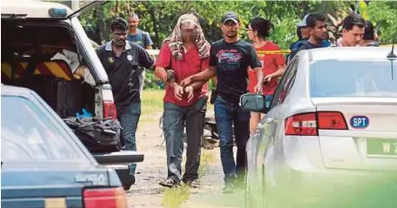  ?? PIC BY AMIR IRSYAD OMAR ?? The murder suspect being escorted by plain-clothes police officers at the scene of the crime in Kampung Sama Gagah, Permatang Pauh, yesterday.