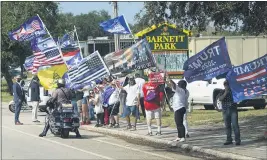  ?? JOHN RAOUX — THE ASSOCIATED PRESS ?? A group of President Donald Trump supporters wave flags along the street as Democratic vice presidenti­al candidate Sen. Kamala Harris, D-Calif., arrives at a campaign event Monday in Orlando, Fla.