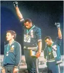  ??  ?? Tommie Smith (centre) and John Carlos hold gloved fists high.