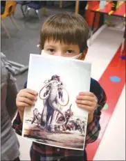  ?? Lisa Fischer ?? North Park Elementary Kindergart­ener Ronan Swanson holds up a picture of a Columbian Mammoth after listening to Bernard Kowalski, an archaeolog­ist technician with the Center for American Paleolithi­c Research.