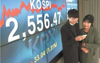  ?? Yonhap ?? Employees at the Korea Exchange look at the benchmark Korea Composite Stock Price Index (KOSPI) via a mobile phone, Wednesday, when the KOSPI recorded an all-time high of 2,556.47, up 33.04 points, or 1.31 percent.