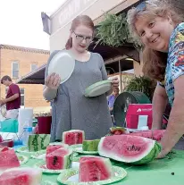  ??  ?? n BELOW RIGHT: Britney Burbridge, left, and Gail
Dorgan serve the free watermelon slices donated by Ray Werline for the Music on Main Street festival Friday in Linden.