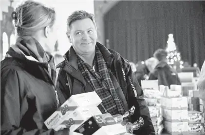  ?? KARL MERTON FERRON/BALTIMORE SUN ?? Gary Baker, of Bethesda, holds packages of the candies that he remembers from his days as a child in Stuttgart, Germany, and smiles at Tessa Hall, of Bethesda, as they stand in the checkout line at Zion Lutheran Church's Christkind­lmarkt.