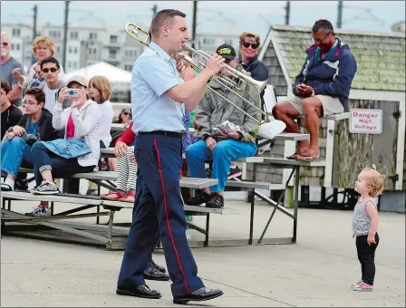  ?? SARAH GORDON/THE DAY ?? A member of the United States Coast Guard Dixieland Band walks through the audience on the Custom House Pier during the opening day of Sailfest on Friday at Waterfront Park in New London. The annual street festival is in its 40th year and continues...