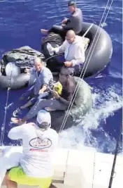  ?? CAPT. GREG HARTLAUB Takedown_Charters on Instagram ?? Mike Diaz, a mate on the Takedown Charters fishing boat out of Islamorada, passes a lit cigarette to four men who migrated by inner tube from Cuba. Diaz and his boss, Capt. Greg Hartlaub, encountere­d the men on May 6.