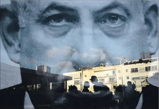  ?? ODED BALILTY / AP ?? Una protesta en Tel Aviv contra la ley del Estado judío, vista a través de un cartel con la imagen del primer ministro, Beniamin Netanyahu