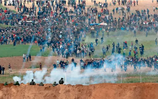  ?? AFP ?? Tear gas grenades falling during the Palestinia­n tent city protest commemorat­ing land day, with Israeli soldiers seen taking positions in the southern Israeli kibbutz of nahal oz across the border from the gaza strip. land day marks the killing of six...