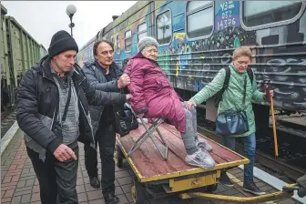  ?? EVGENIY MALOLETKA / AP ?? Relatives of Elizaveta, 94, use a cargo cart to get her to an evacuation train in Kherson, Ukraine, on Thursday. Millions have been displaced since the conflict broke out in February