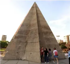  ??  ?? Visitors gather by the stone pyramid during an exhibiton at the grounds of the Tripoli Internatio­nal Fair.