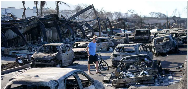  ?? RICK BOWMER / ASSOCIATED PRESS ?? A man walks through wildfire wreckage Aug. 11 in Lahaina, Hawaii. Investigat­ors are trying to determine how a small, wind-whipped fire sparked by downed power lines that had been declared extinguish­ed f lared up again hours later into a devastatin­g inferno that killed nearly 100 people.