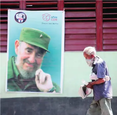  ?? EFE ?? Un hombre con mascarilla pasa junto a una foto de Fidel Castro en una calle de La Habana