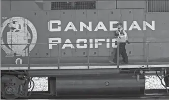  ?? CP PHOTO ?? A Canadian Pacific Railway employee walks along the side of a locomotive in a marshallin­g yard in Calgary. Canadian Pacific Railway and the Teamsters Canada Rail Conference say they have reached a four-year tentative agreement to end a strike hours after it began.