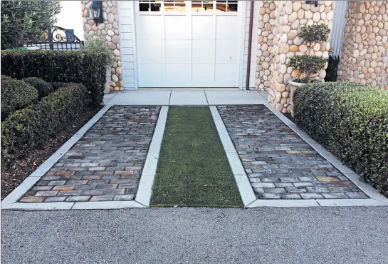  ?? MARGARET MAYFIELD/AP ?? In dry and mild climates, a grass driveway may work perfectly well, particular­ly if two wide gravel or impermeabl­e paved strips are included.