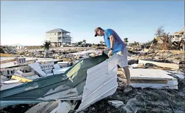  ?? David Goldman Associated Press ?? MIKE JACKSON sifts through the ruins of his home in Mexico Beach, Fla., after Hurricane Michael.