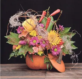  ?? PROVIDED BY RITTNERS FLORAL SCHOOL ?? For a festive fall centerpiec­e, try hollowing out a pumpkin. Drop in a plastic liner or a glass vase filled with floral foam. Fill the foam with seasonal flowers, branch material, Spanish moss and dried peppers or pepper berries. Prop the pumpkin top against the arrangemen­t as a finishing touch.