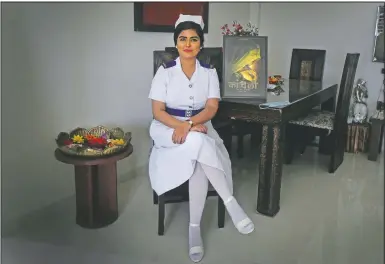  ?? (AP/Rafiq Maqbool) ?? Shikha Malhotra, a Bollywood actress and nurse, poses for a photo sitting next to a poster of her in a Bollywood film at her apartment in Mumbai, India.