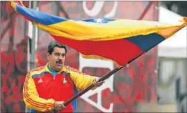  ?? JORGE SILVA / REUTERS ?? Maduro fa onejar una bandera davant el palau de Miraflores