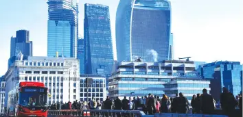  ?? — Reuters ?? Workers cross London Bridge with City of London skyscraper­s behind during the morning rush hour in London, Britain.