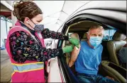  ?? MICHAEL HOLAHAN/THE AUGUSTA CHRONICLE VIA AP ?? Registered Nurse Lisa Strickland administer­s a COVID-19 vaccine shot Tuesday to Tracy Atkinson during a driveup inoculatio­n at Craig Houghton Elementary School in Augusta.