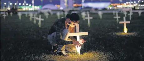  ?? REUTERS ?? A man lights a candle next to a cross symbolisin­g the ones who died from the coronaviru­s disease, in front of the National Congress in Brasilia, Brazil.
