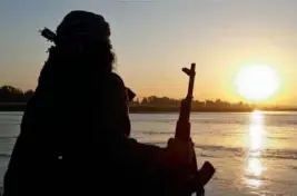  ?? — AP ?? In this photo released on September 29, 2014 by a militant website, which has been verified and is consistent with other AP reporting, an Islamic State fighter holds his AK- 47 assault rifle as he relaxes on the bank of the Euphrates river in Raqqa,...