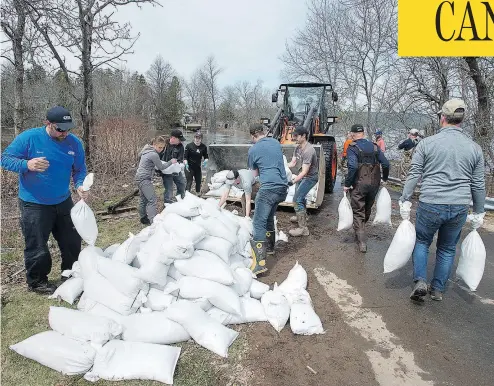  ?? ANDREW VAUGHAN/THE CANADIAN PRESS ?? Residents and volunteers load sandbags in Rothesay, N.B., on Sunday. Rivers across New Brunswick are still rising, flooding streets and properties and forcing people from their homes in several communitie­s.