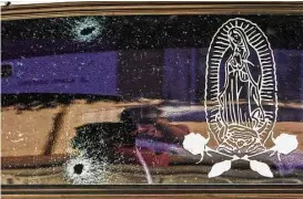  ?? Rashide Frias / Associated Press ?? A car’s rear windshield is held together by a film with an image of the Virgin of Guadalupe after being struck during gunfire involving Mexican marines.