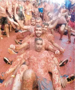  ?? JOSE JORDAN/GETTY-AFP ?? Revelers soak in tomato pulp on Wednesday during the annual “Tomatina” street fight in Bunol, Spain. The battle returned after a hiatus due to the pandemic. Tons of overripe tomatoes were left on city streets for up to 20,000 participan­ts to throw.