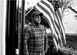  ?? SARAH BLAKE MORGAN/AP ?? Zia Ghafoori stands beside an American flag hanging at his Charlotte, North Carolina, home. The Afghan interprete­r spent 14 years working alongside U.S. Special Forces.