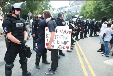  ?? MIKE BLAKE / REUTERS ?? A demonstrat­or protesting the police shooting of Keith Scott hugs a police officer in Charlotte, North Carolina, on Sunday.